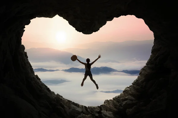 Woman leaps inside cave at mountain — Stock Photo, Image