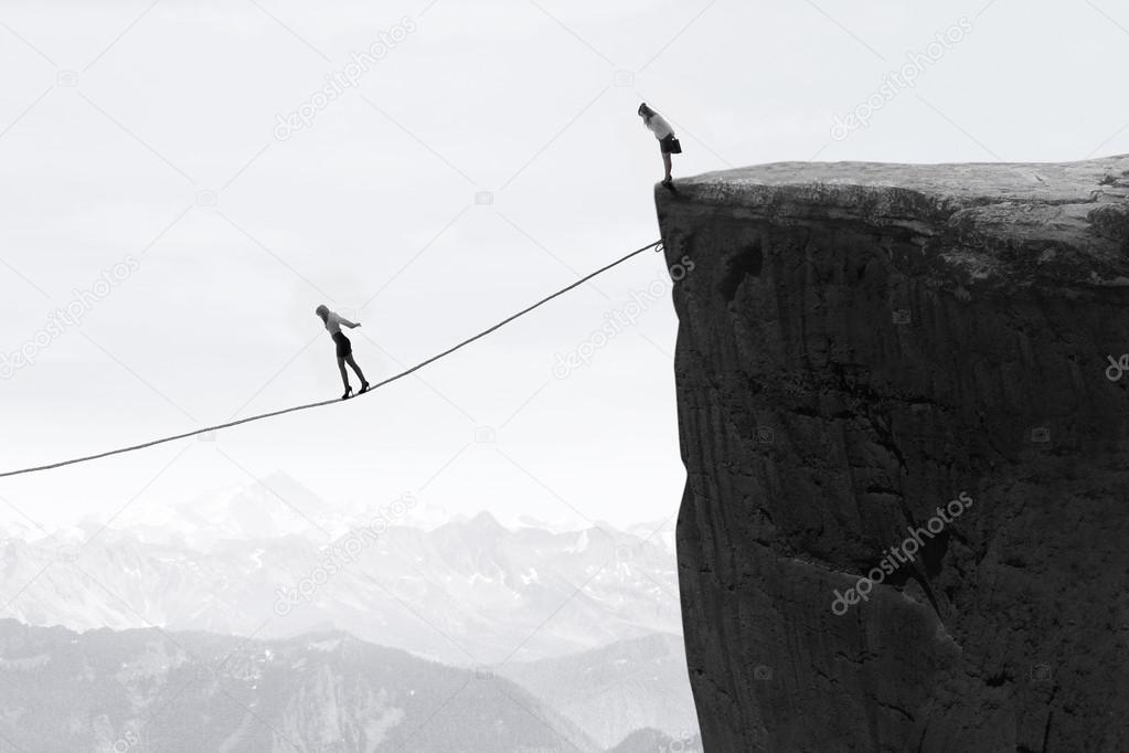 Businesswoman walking on the rope over the gap