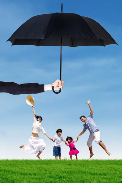 Attractive family jumping at field under umbrella — Stock Photo, Image