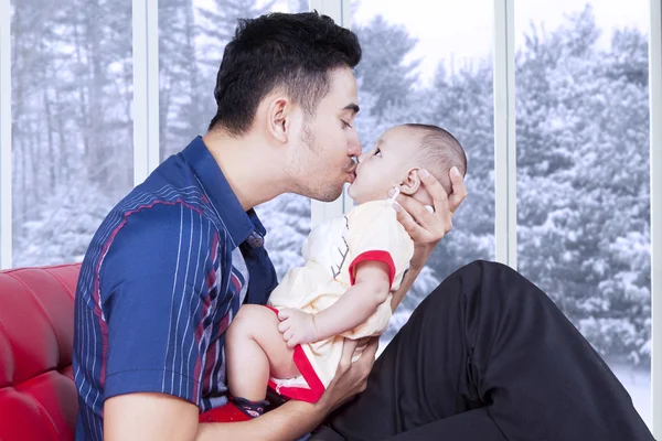 Papá sentado en el sofá y besar a su bebé — Foto de Stock