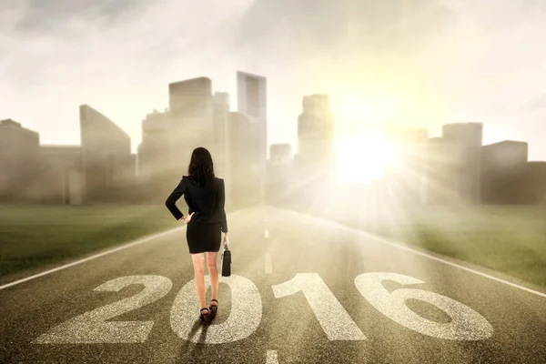 Vrouwelijke werknemer lopen op de weg met getallen 2016 — Stockfoto