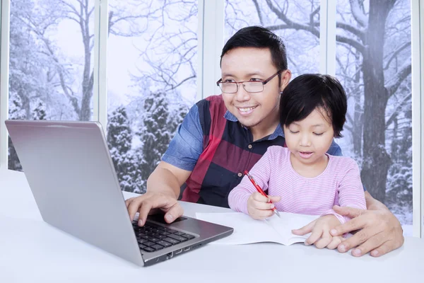 Father using laptop while helps his child studying — Stockfoto