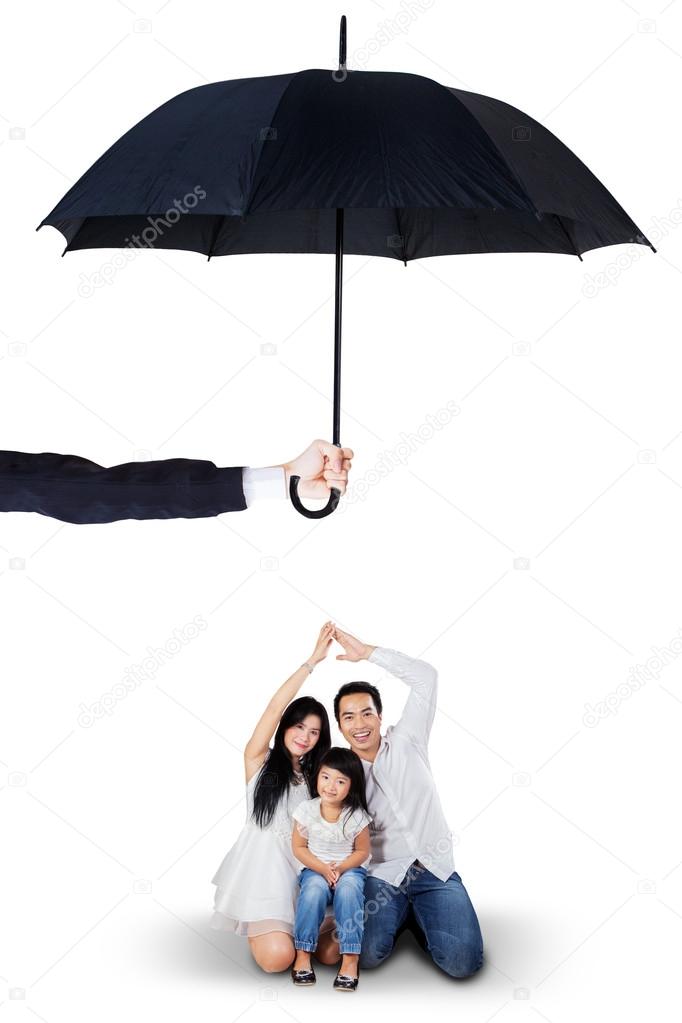 Attractive family sitting under umbrella in studio