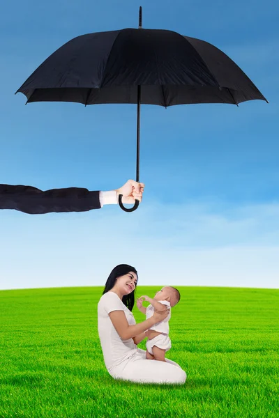 Mother and her baby playing under umbrella at field — Stok fotoğraf