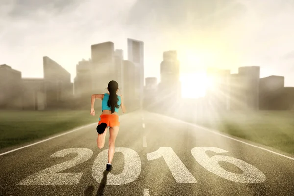 Mulher corre na estrada com números 2016 — Fotografia de Stock