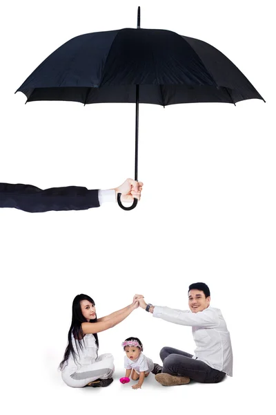 Young parents playing with their daughter under umbrella — Zdjęcie stockowe