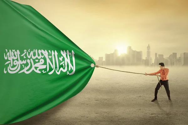 Persona árabe arrastrando la bandera de Arabia Saudita —  Fotos de Stock