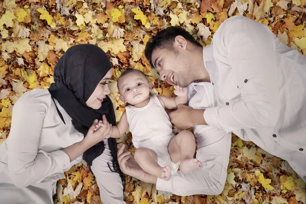 Bambino e genitori sdraiati sulle foglie autunnali — Foto Stock