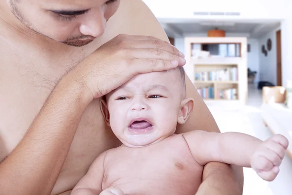 Sjuk baby gråter på far händerna — Stockfoto
