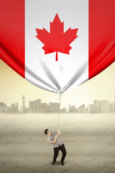 年轻男子拉下加拿大国旗 — 图库照片
