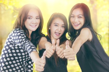 Cheerful teenager girls show thumbs up