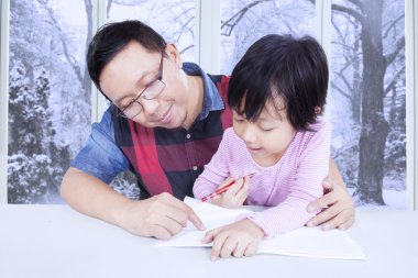 Cute little girl doing homework with dad
