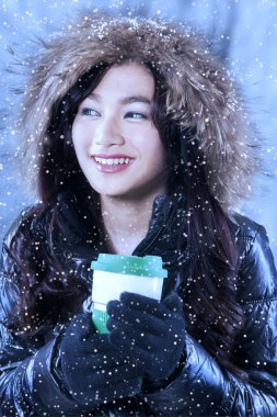 Girl with warm jacket holds hot drink