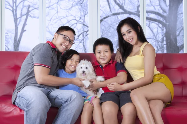 Beautiful family sitting on sofa with puppy — Stockfoto