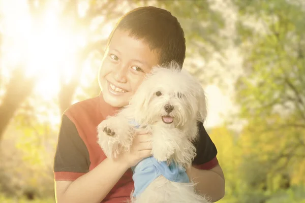 Carino ragazzo abbracciare il suo cucciolo al parco — Foto Stock