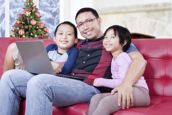 Cute children and dad with laptop on sofa — Zdjęcie stockowe