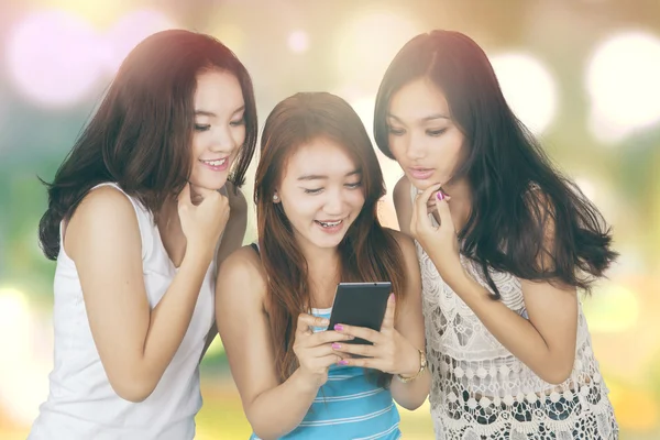 Girls using cellphone with bokeh background — Stockfoto