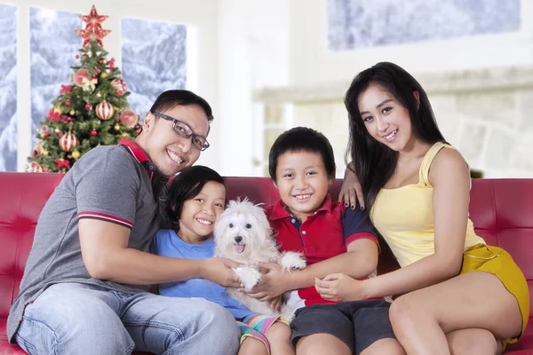 Happy family holding dog on sofa — 스톡 사진