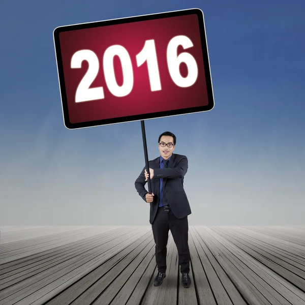 Male worker lifts numbers 2016 with a board — Stock Photo, Image