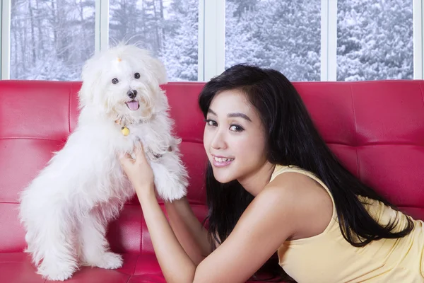 Femme couchée sur le canapé tout en jouant avec le chien — Photo