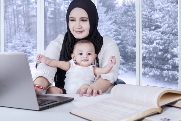 Jeune mère travaillant avec son bébé — Photo