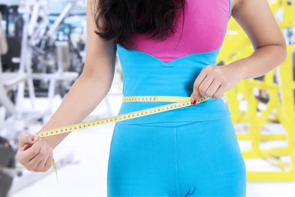 Närbild av kvinnliga tränare mäta hennes mage — Stockfoto