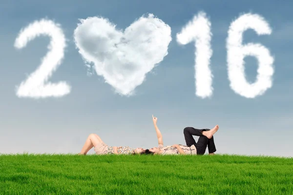 Paar liggen op gras onder nummers 2016 — Stockfoto