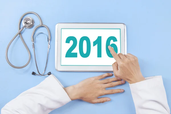 Médecin main touchant numéro 2016 sur la tablette — Photo