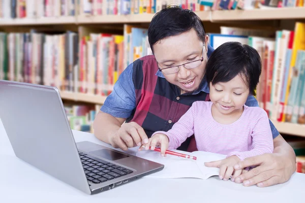 Menina aprender a escrever na biblioteca com um professor — Fotografia de Stock