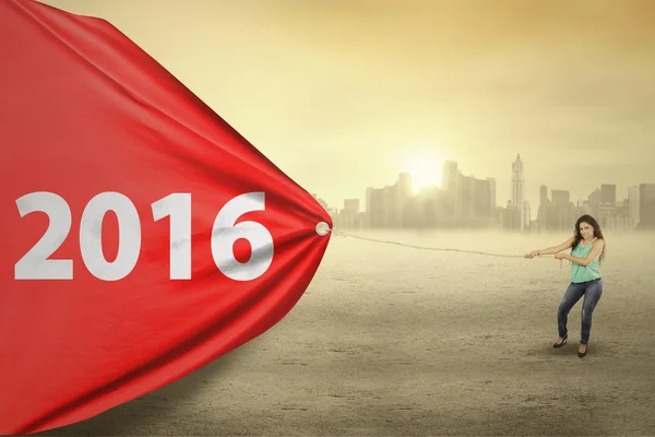 Mujer arrastrando bandera roja con números 2016 — Foto de Stock