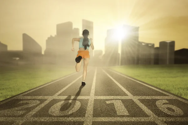 Mujer empezar a correr con los números 2016 en el campo — Foto de Stock