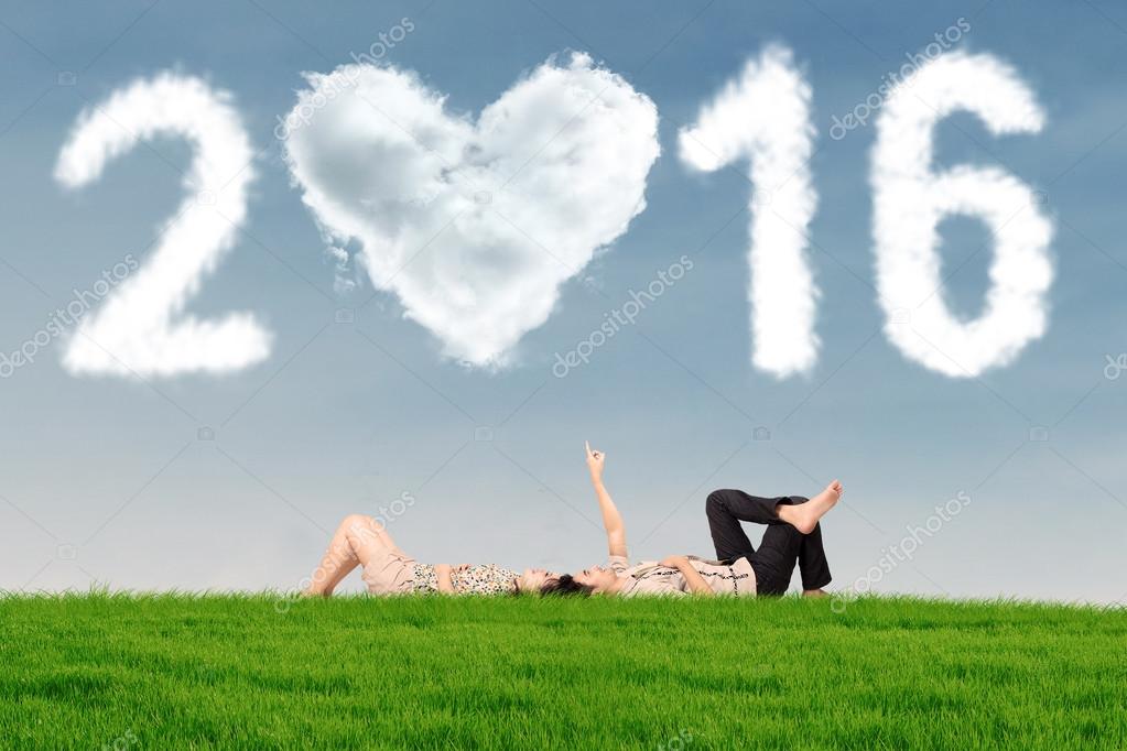 Couple lying on grass under numbers 2016