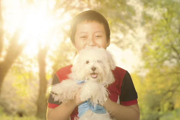 Bonito menino segurando seu cão no parque — Fotografia de Stock