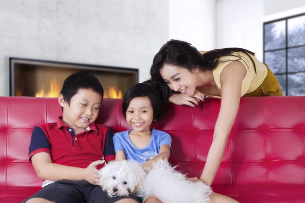 Bonita madre e hijos jugando a su perro en casa — Foto de Stock