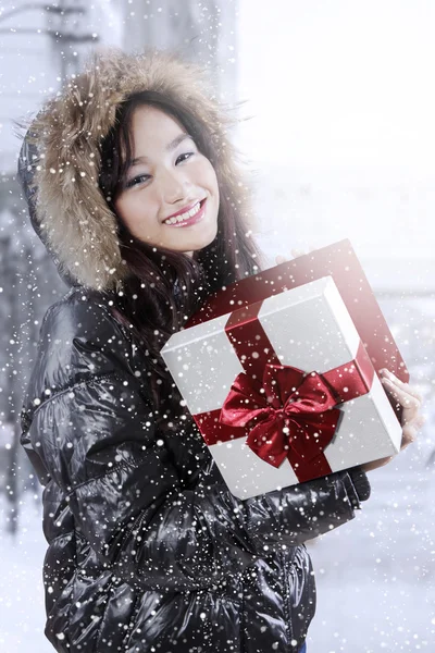 Niedliches Mädchen mit Winterjacke und hält Geschenkbox — Stockfoto