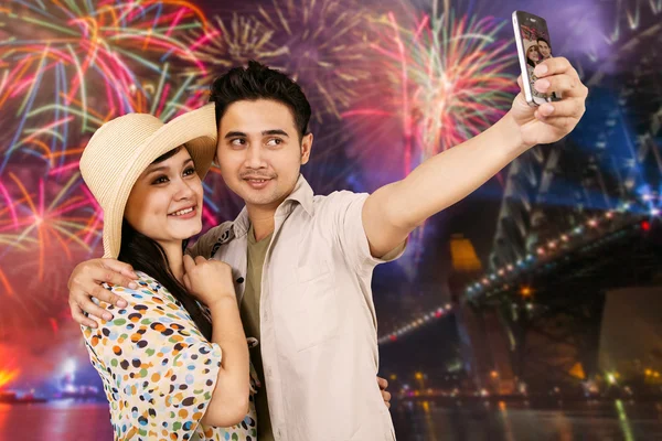 Pareja feliz tomando selfie con fondo de fuegos artificiales —  Fotos de Stock