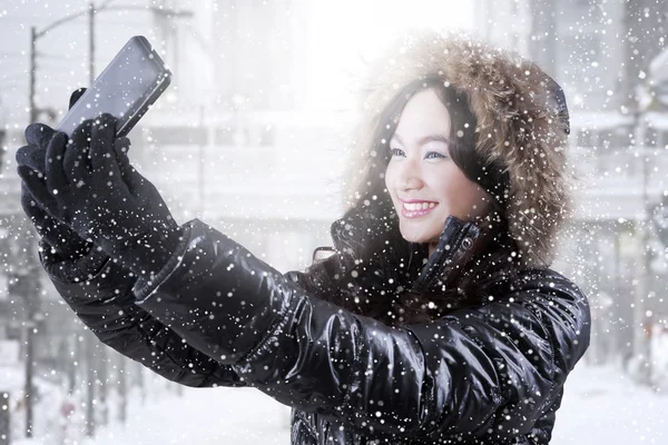 Glückliches Mädchen mit Wintermantel macht Selfie — Stockfoto