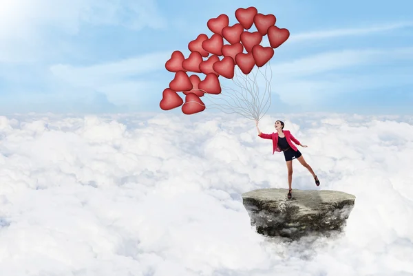 Mujer feliz y globos sobre las nubes — Foto de Stock