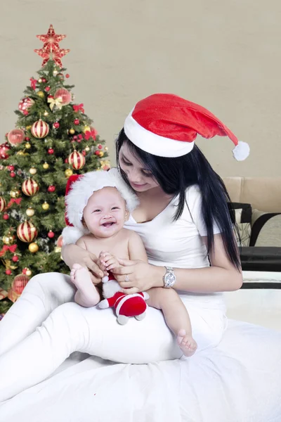 Mãe e seu bebê com árvore de Natal no quarto — Fotografia de Stock