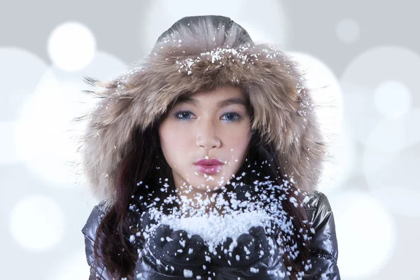 Teini tyttö puhaltaa lunta bokeh tausta — kuvapankkivalokuva