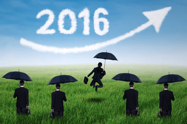 Entrepreneurs with umbrella and numbers 2016 at field — Stock Photo, Image