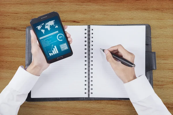 Man Hands Holds Mobile Phone while Writing — Stock Photo, Image