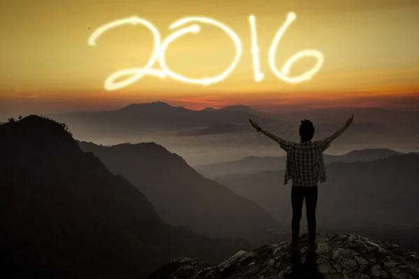 Hombre de pie en el pico de la montaña con números 2016 — Foto de Stock