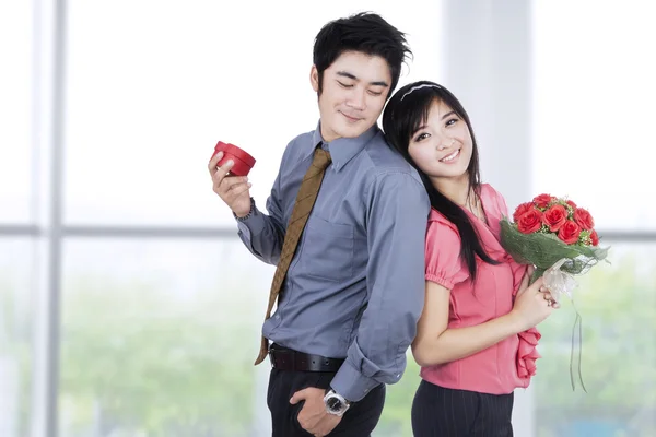 Casal jovem com uma caixa de presente e flores — Fotografia de Stock