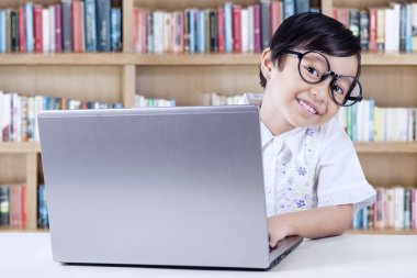 Neşeli öğrenci dizüstü kütüphanede kullanma