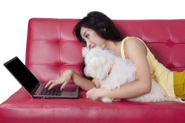 Kız ve köpek kanepede dizüstü bilgisayar kullanmak