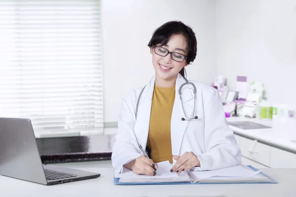 Atraktivní ženský lékař pracující na stůl — Stock fotografie