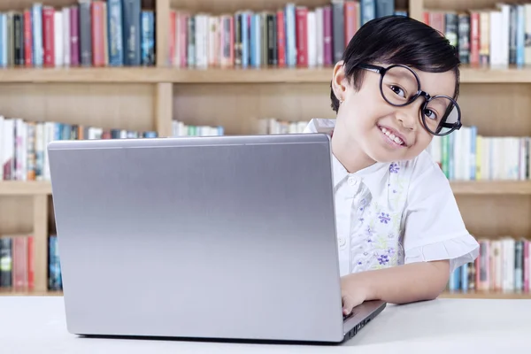 Fröhlicher Schüler mit Laptop in der Bibliothek — Stockfoto