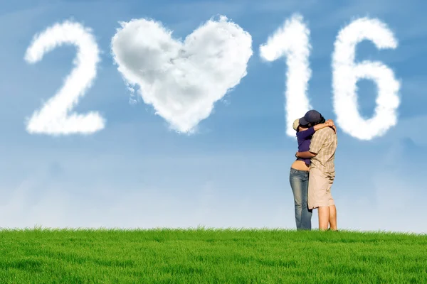 Couple kissing at field with cloud shaped numbers 2016 — Stock Photo, Image