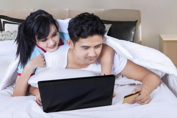Paar gebruiken laptop en credit card in slaapkamer — Stockfoto